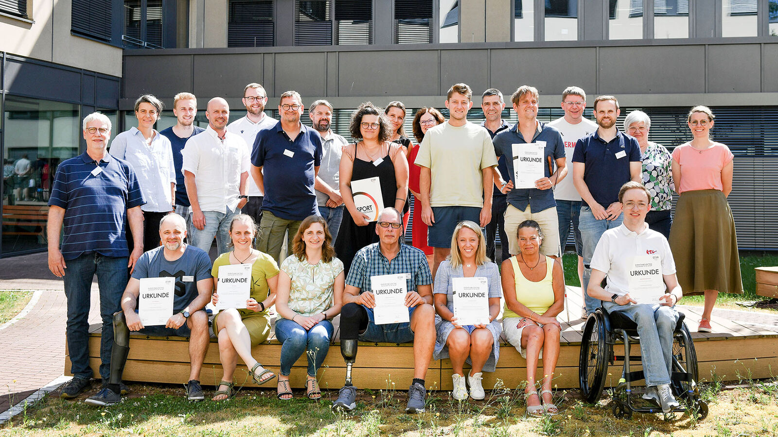Gruppenbild: Frauen und Männer, ein Teil von ihnen hält Abschlussurkunden in der Hand.