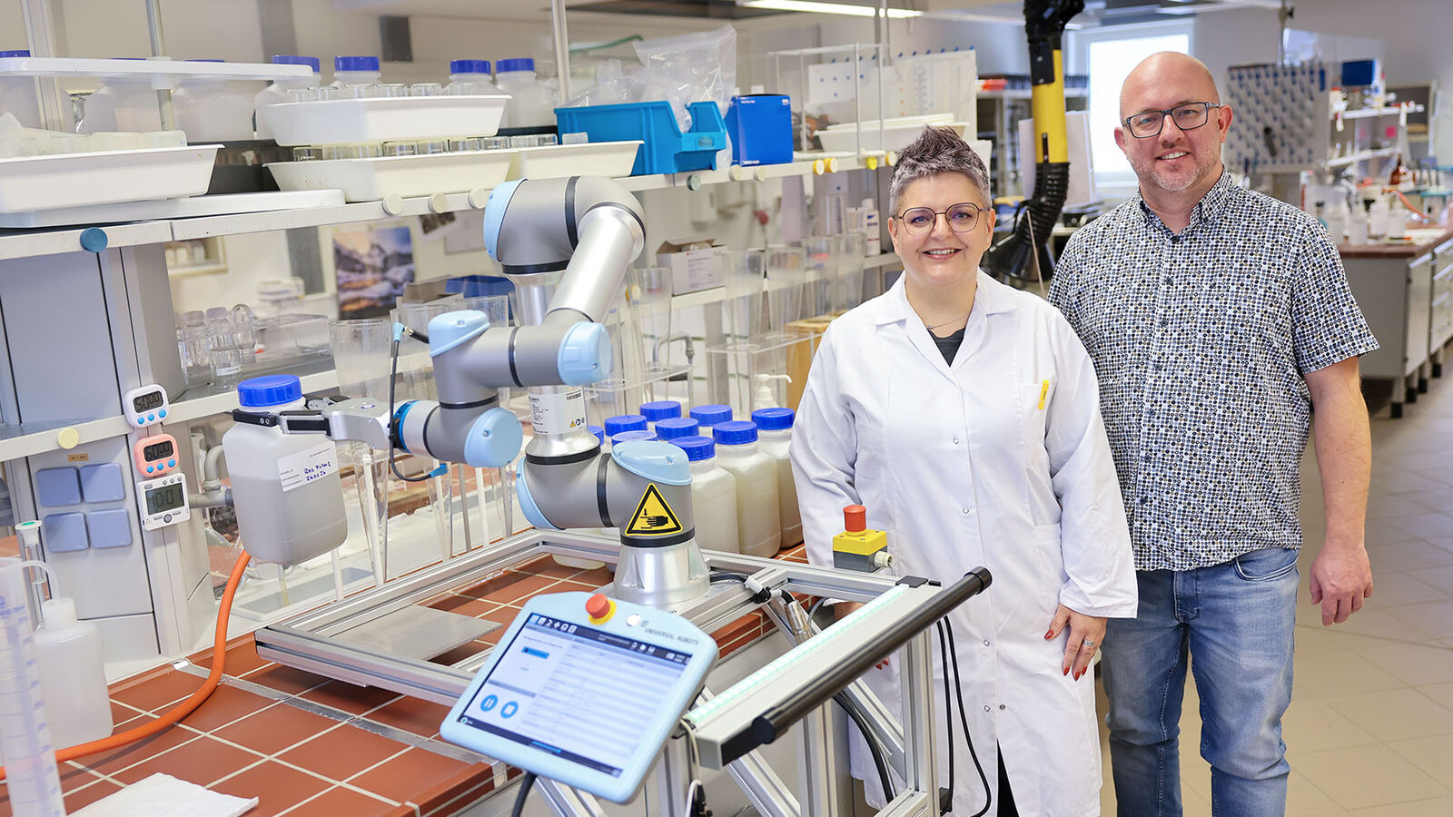 Jost und Simon mit dem Cobot Laborleiterin Jost und TBD-Berater Simon posieren mit dem Roboterkollegen