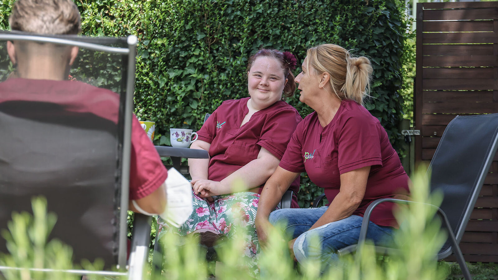 Franziska Wolf sitzt mit ihren Kolleginnen in einem grünen Garten und macht Kaffeepause.