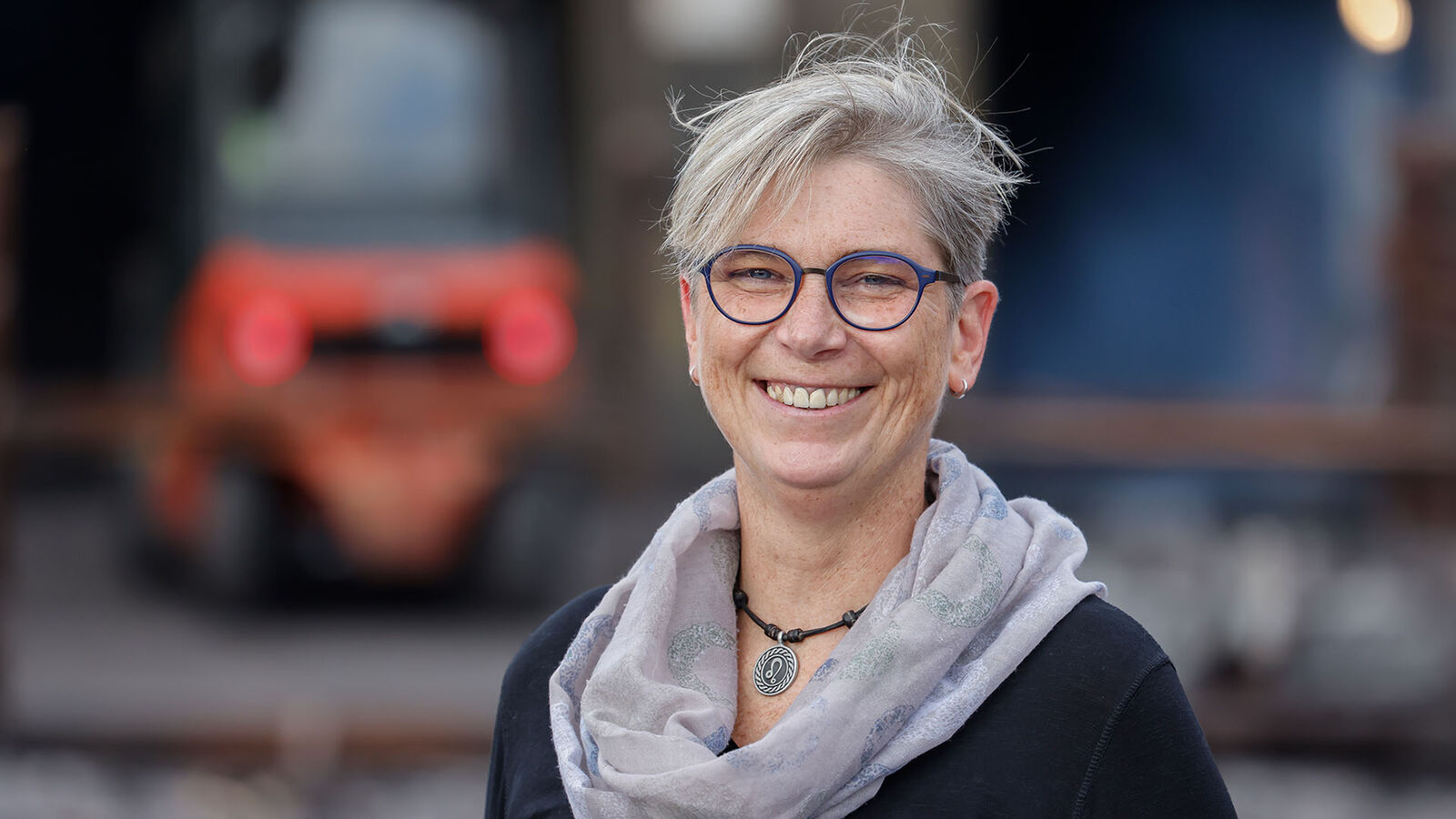 Eisenwerk Brühl, Monika Kern Eine Frau Mitte fünfzig mit grauem Kurzhaarschnitt und Brille lächelt in die Kamera.