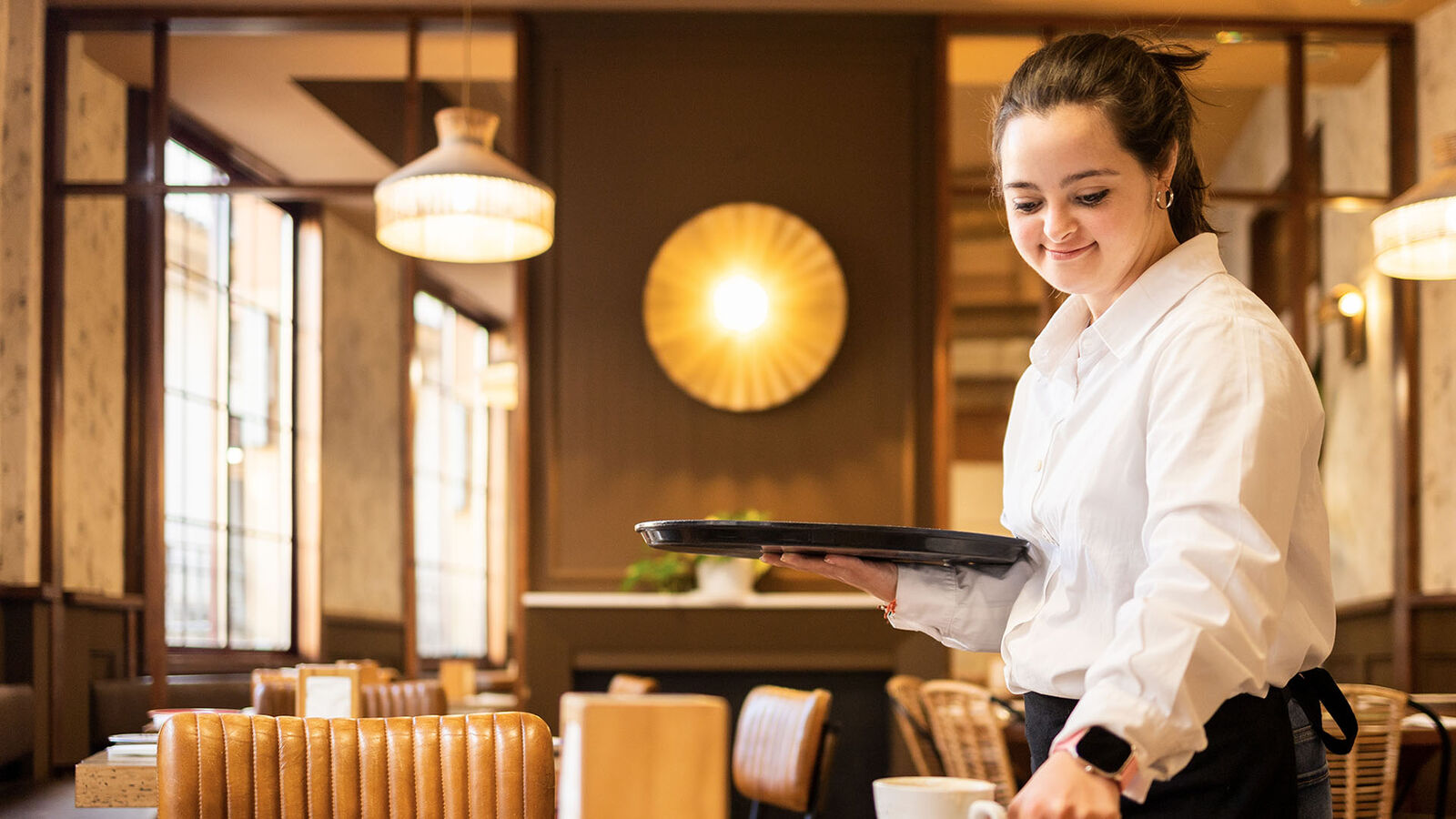 Junge Frau mit Downsyndrom arbeitet in der Gastronomie.