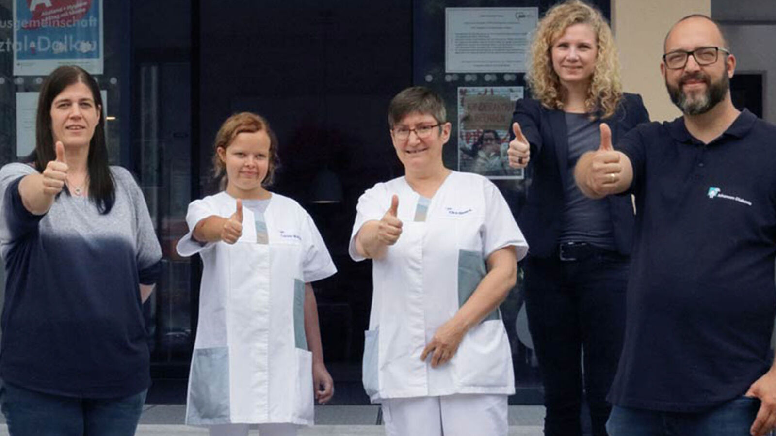 Gruppenbild. Sechs Menschen mit Carolin im Zentrum. Alle zeigen einen hochgereckten Daumen.