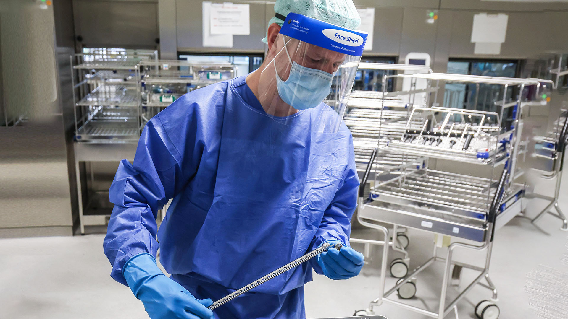 Detailansicht des Reinigungsprozesses, ein Mann in Schutzkleidung hält ein Endoskop in der Hand. 