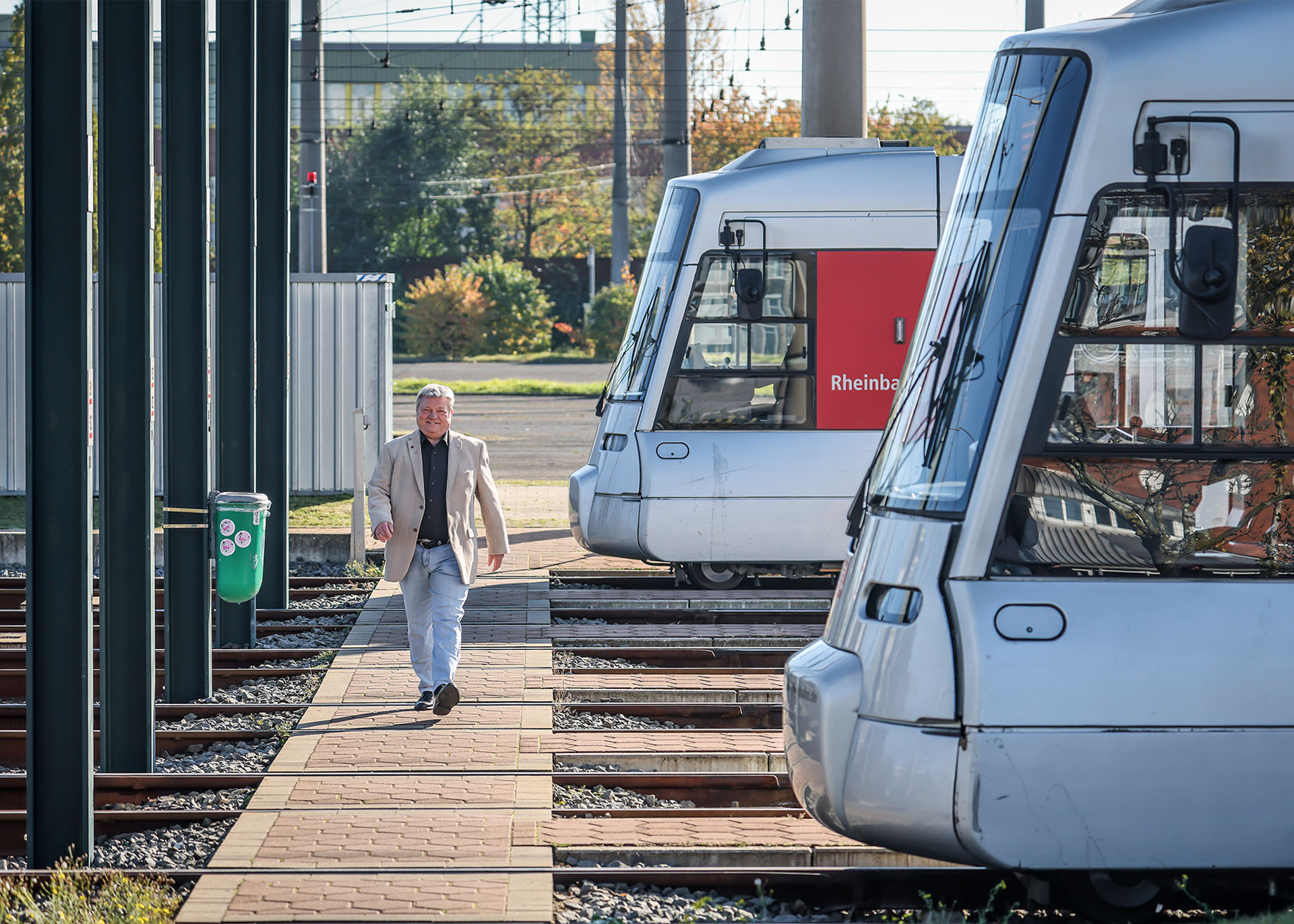 Brings läuft im Straßenbahndepot an einigen geparkten Straßenbahnen vorbei