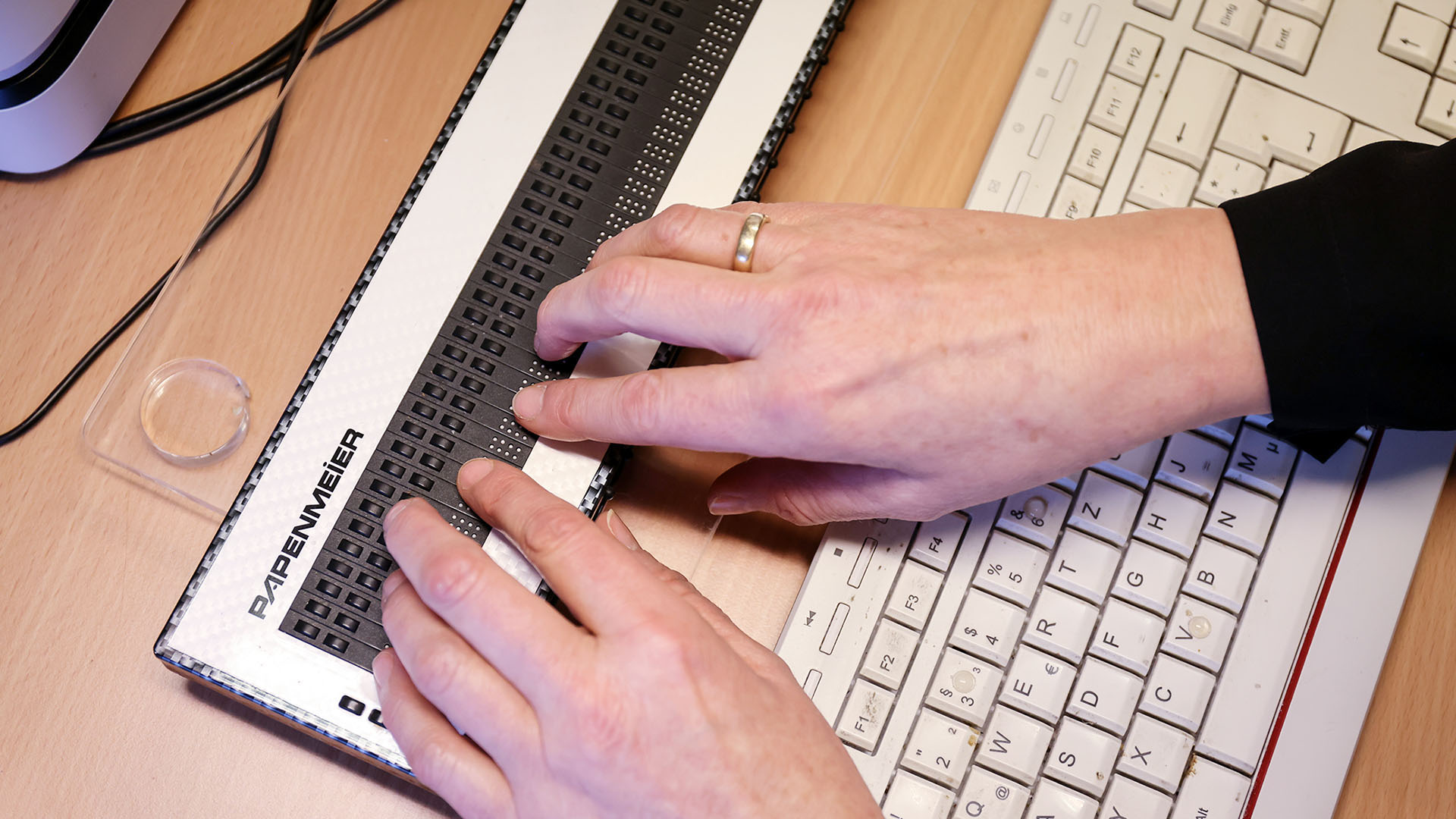 Hände tippen auf einer Braillezeile.