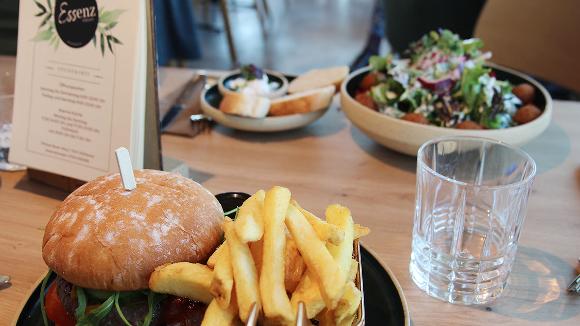 Gedeckter Bistrotisch mit einem Burger- und einem Falafel-Teller.