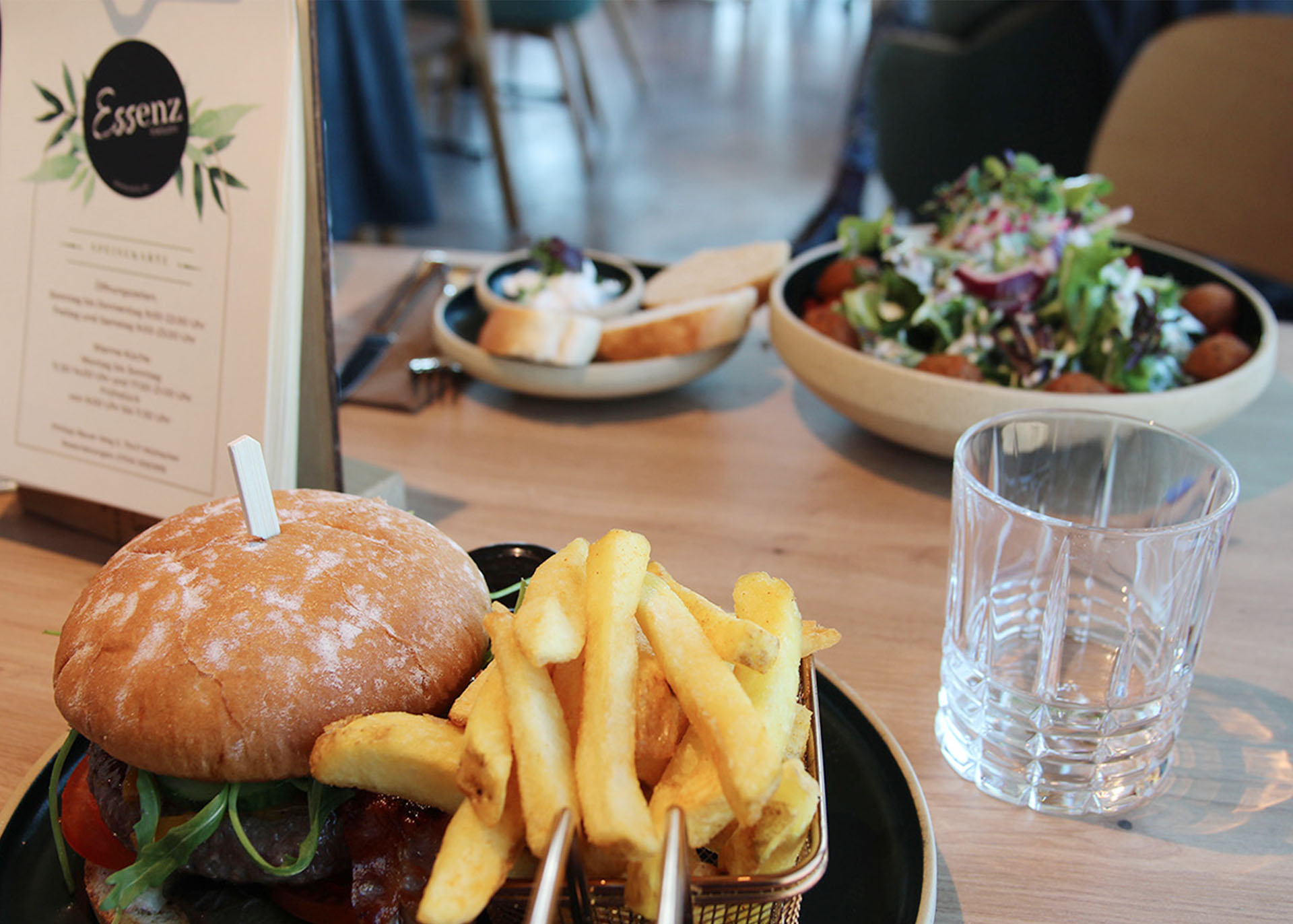 Gedeckter Bistrotisch mit einem Burger- und einem Falafel-Teller.