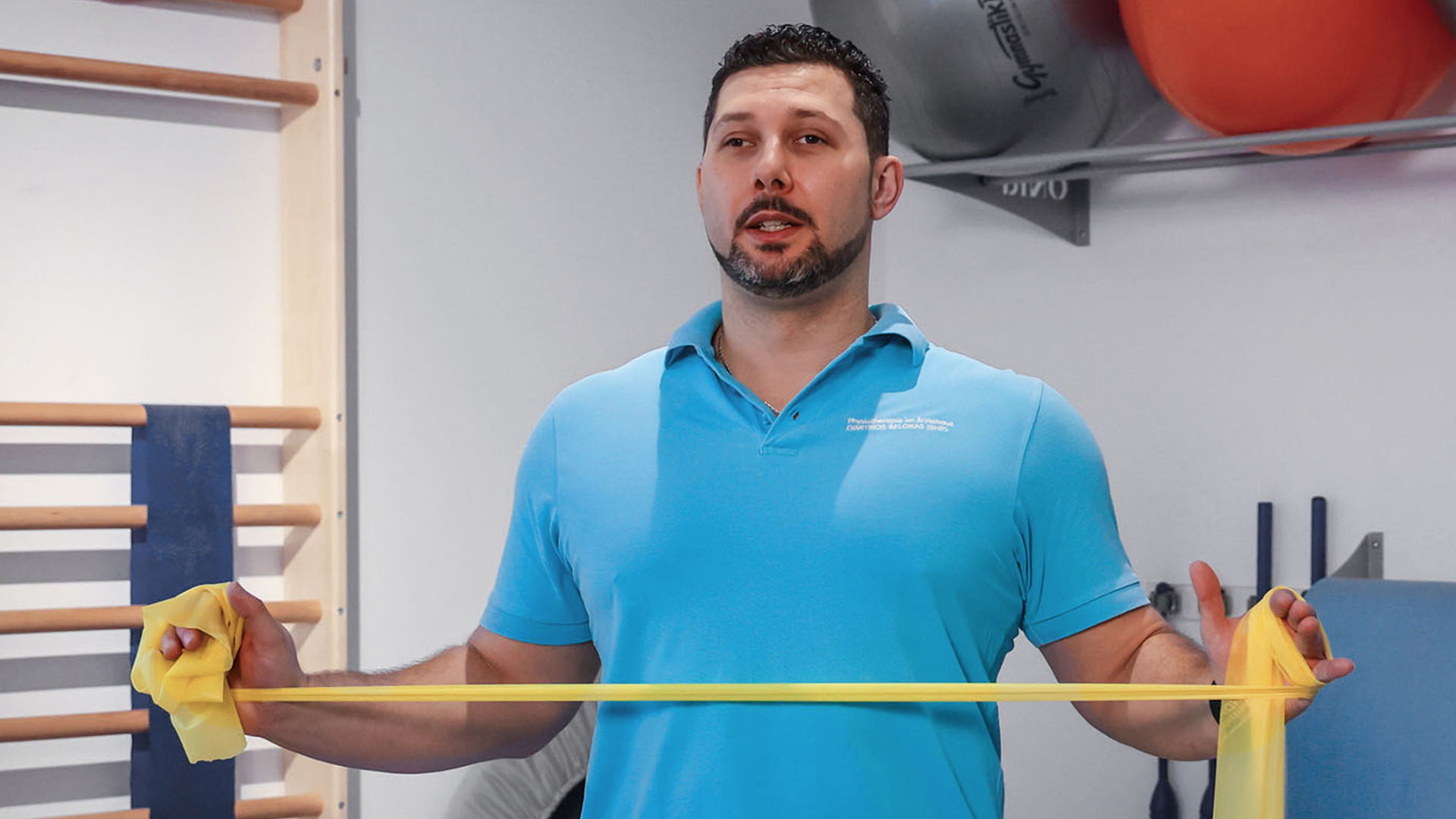 Dimitrios Belokas demonstriert eine Übung mit einem gelben Thera-Band.
