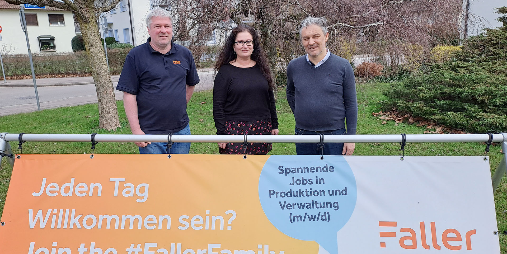 Drei Personen stehen hinter einem großem Transparent mit der Aufschrift „Faller".