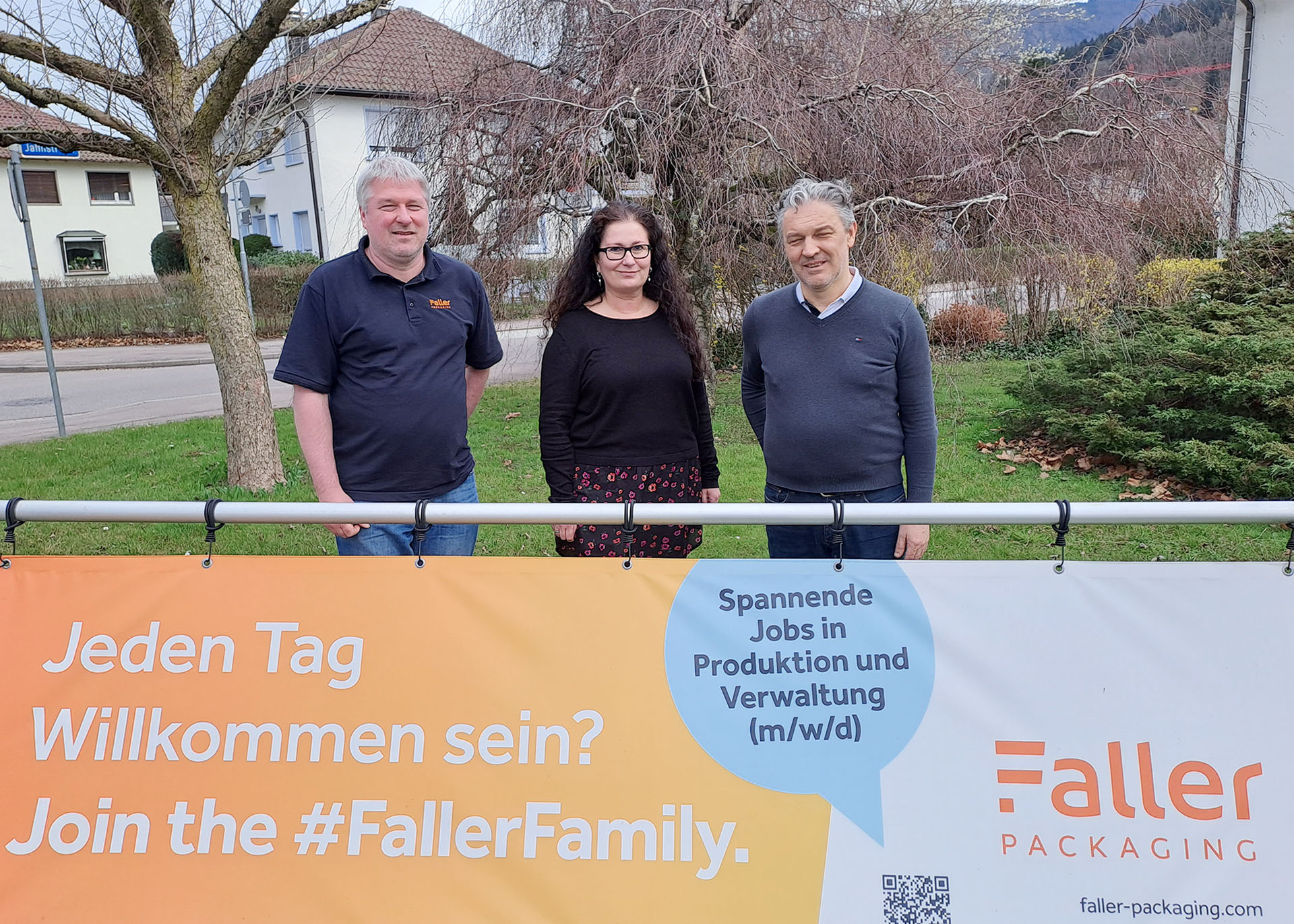 Drei Personen stehen hinter einem großem Transparent mit der Aufschrift „Faller".