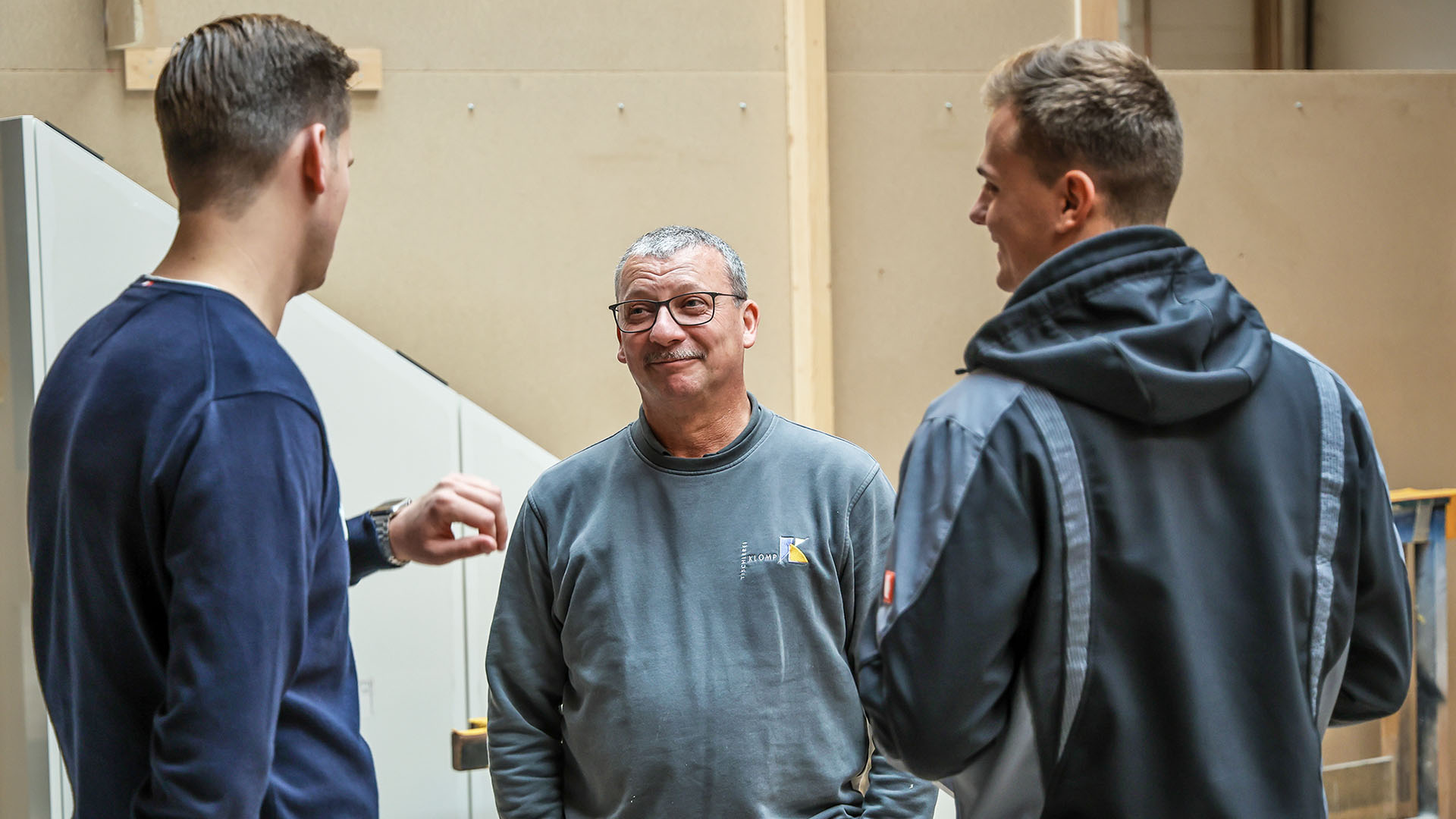 Drei Männer, Stefan Baches in der Mitte unterhalten sich stehend.