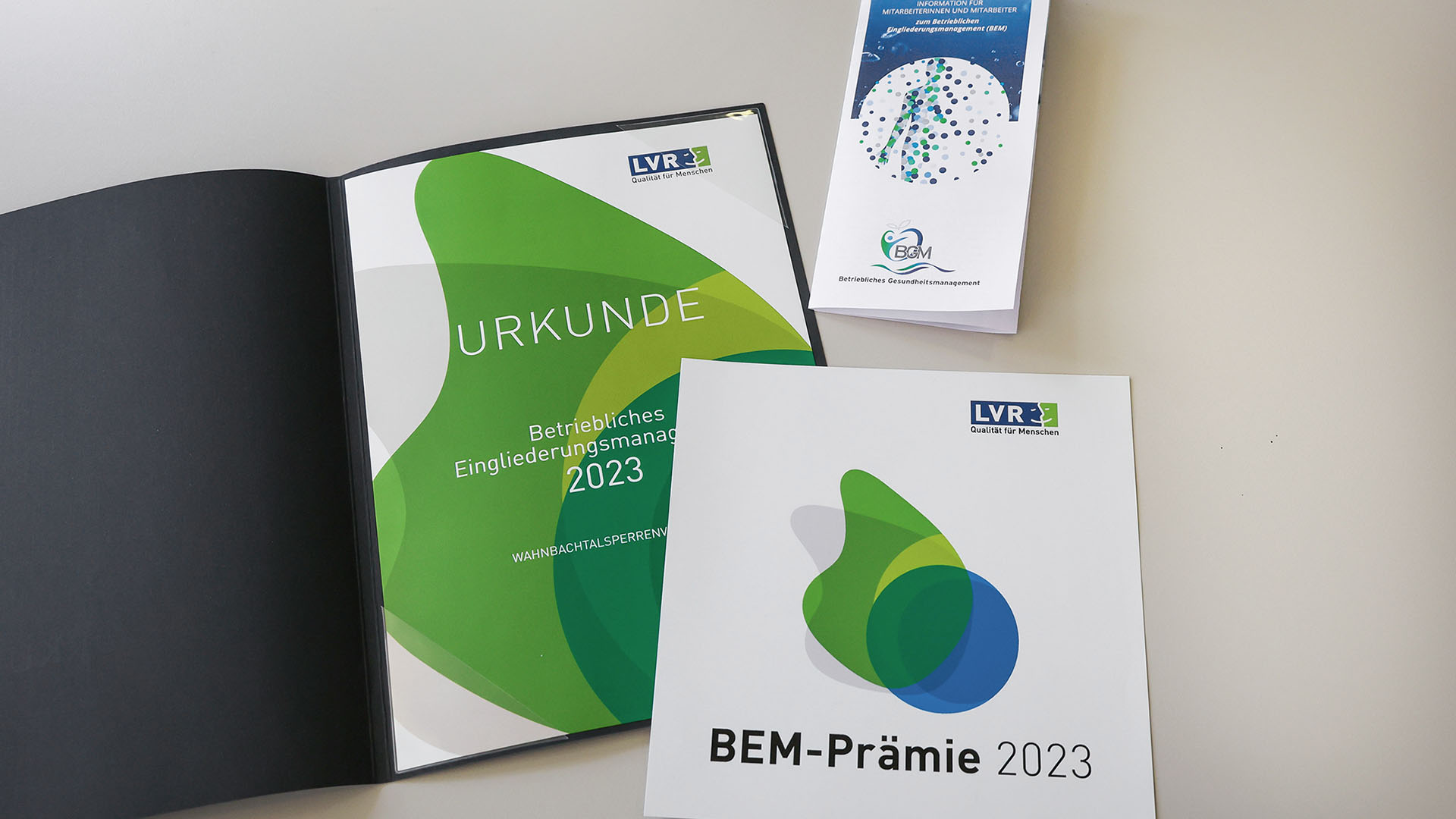 Urkunde und Flyer zum BEM liegen auf einem Tisch.
