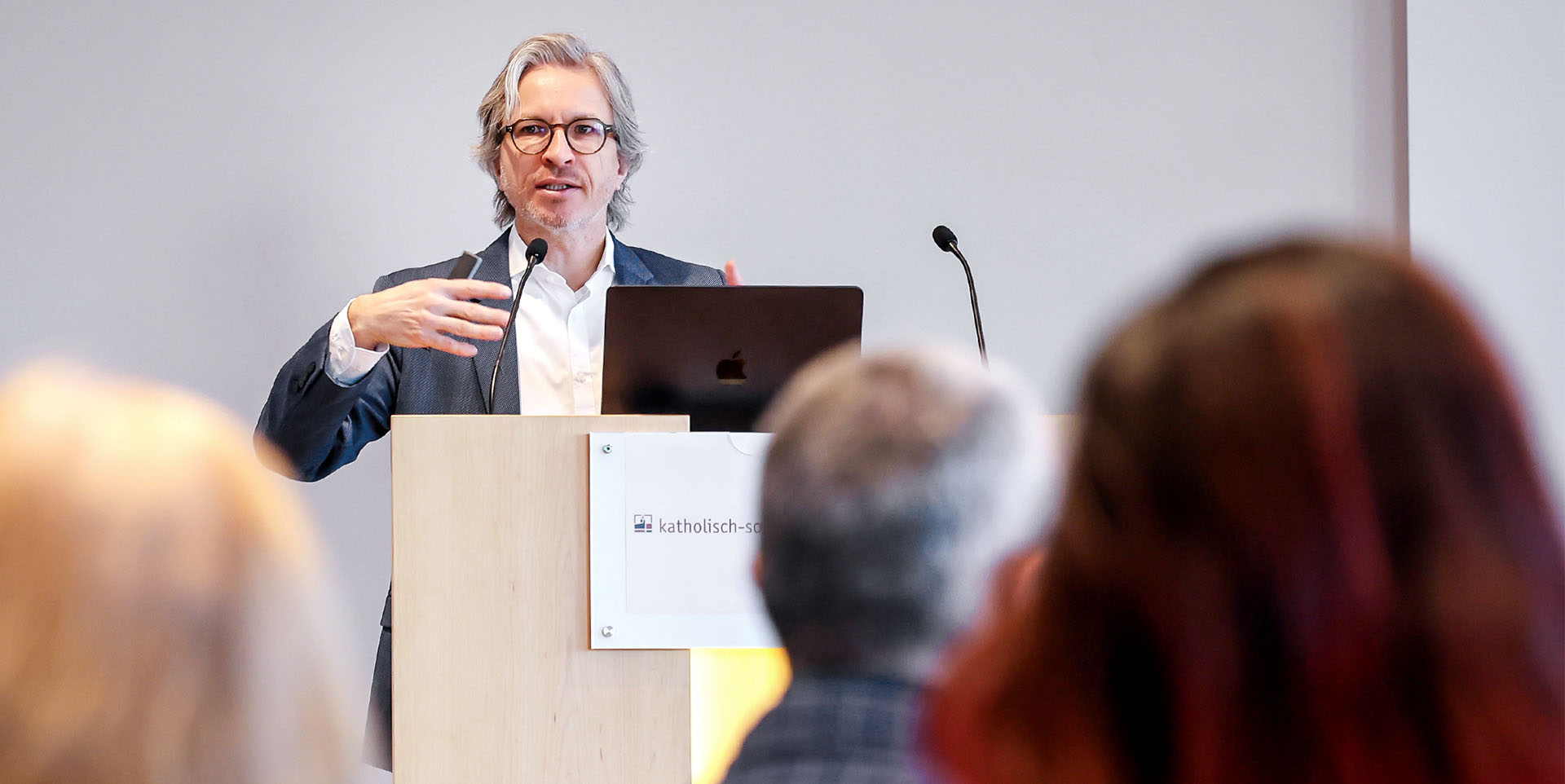 Prof. Dr. Carsten Röcker Ein Herr mittleren Alters, grauen Haaren und gepflegtem Drei-Tage-Bart steht an einem Rednerpult vor einem gut gefüllten Saal und hält einen technischen Vortrag.