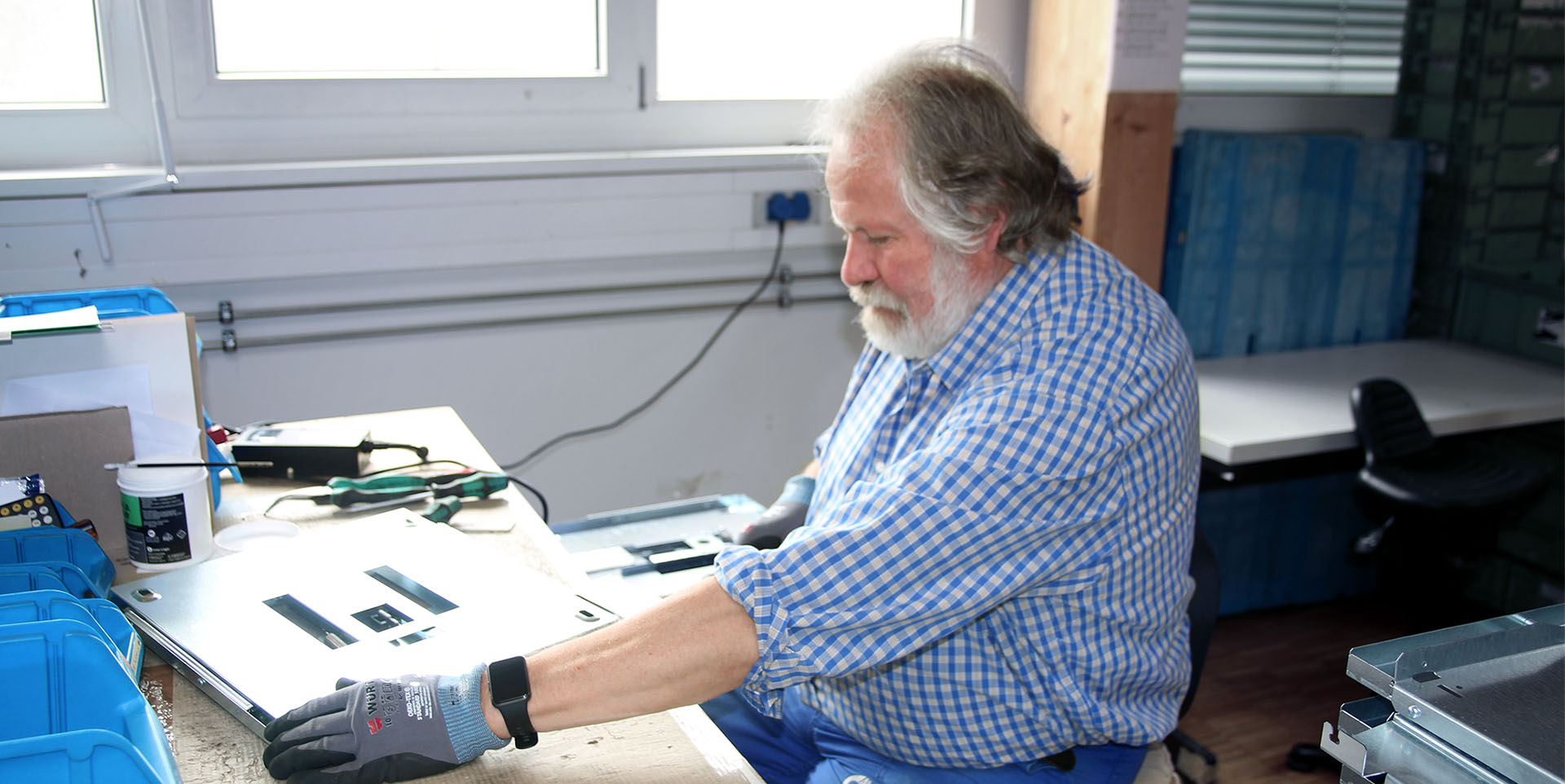 Ein Mann sitzt an einer Werkbank bei der Montage.