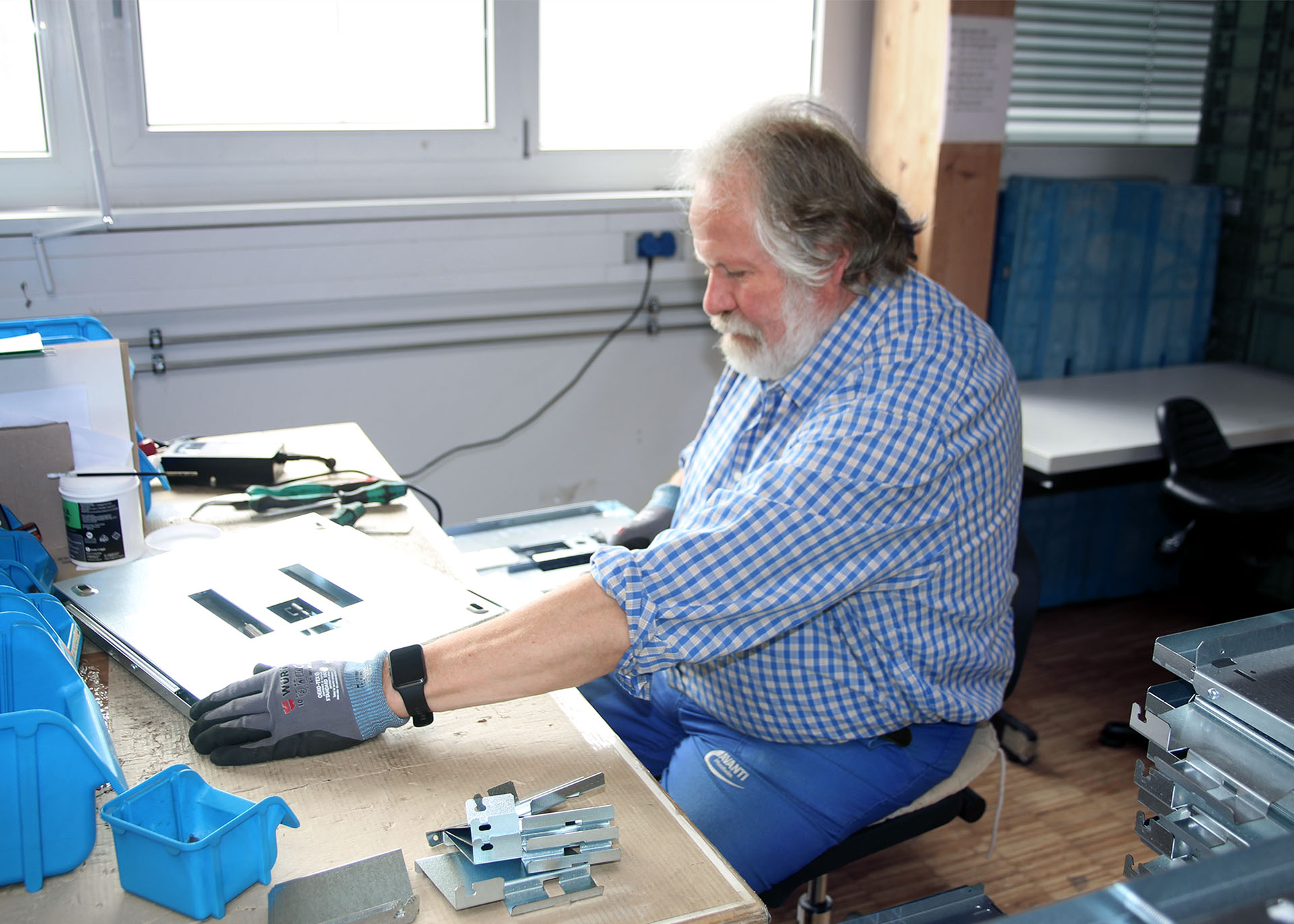 Ein Mann sitzt an einer Werkbank bei der Montage.