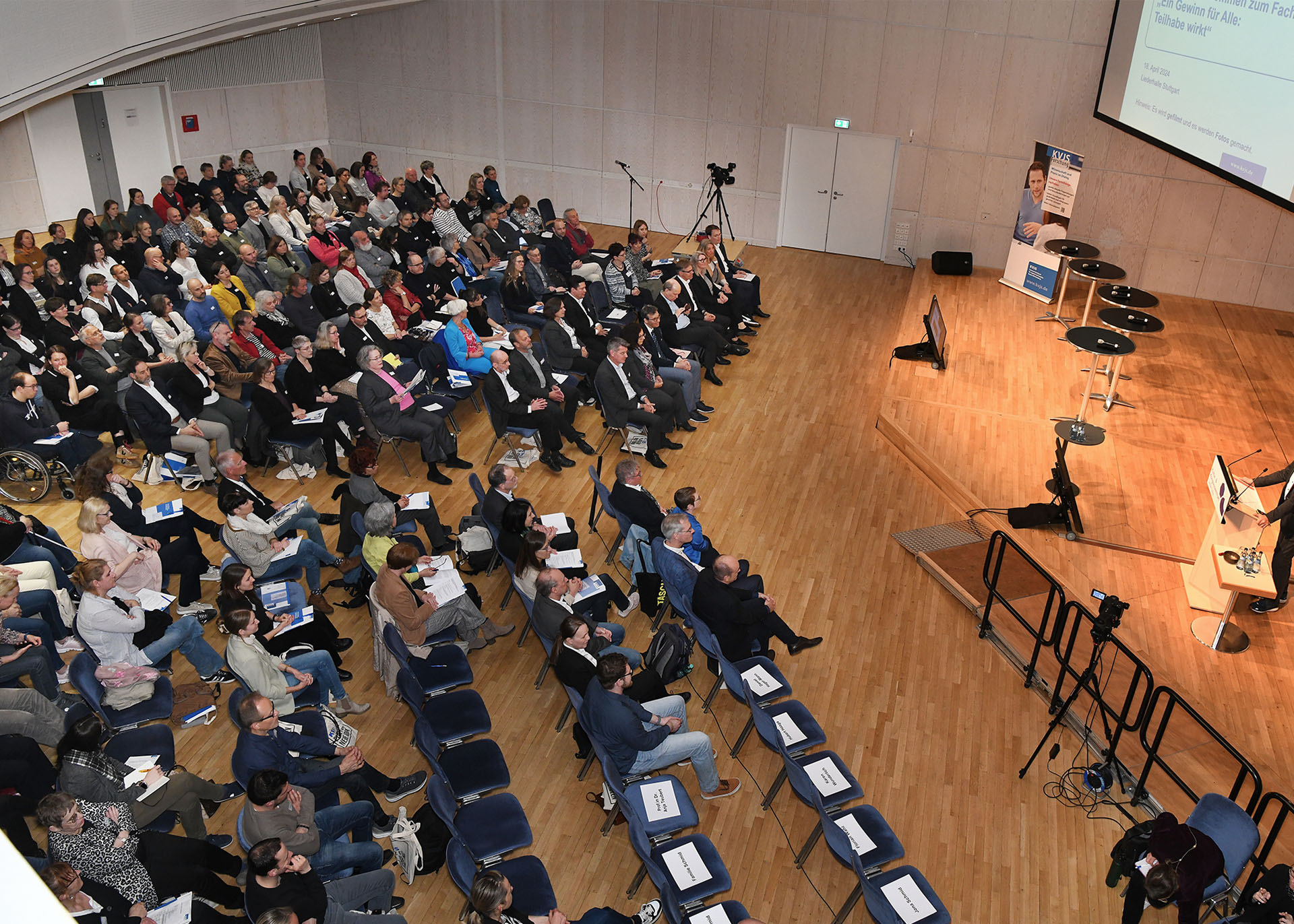 Draufsicht auf die Veranstaltung mit Podium und Publikum