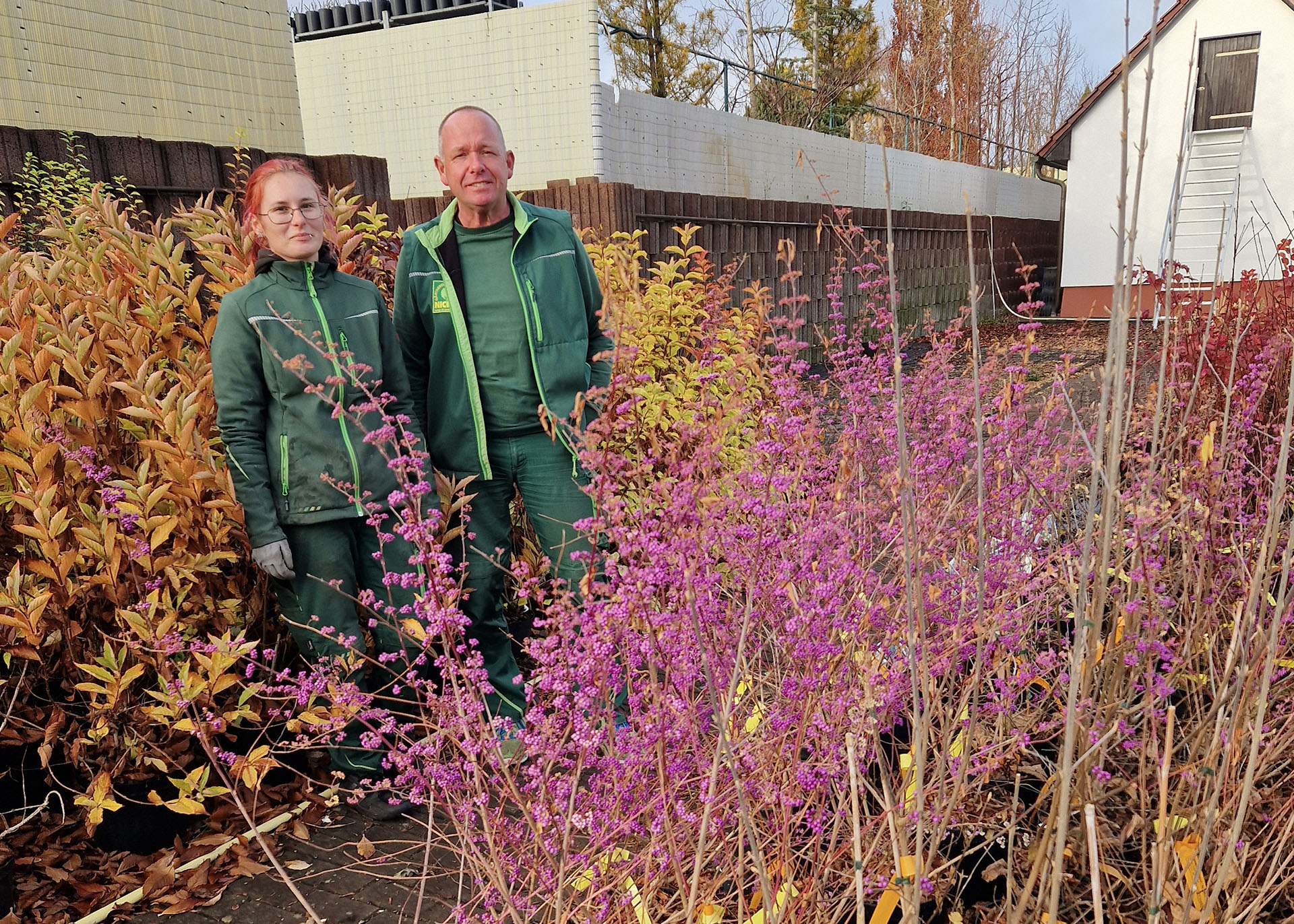 2 Mitarbeitende stehen an einem Blumenbeet