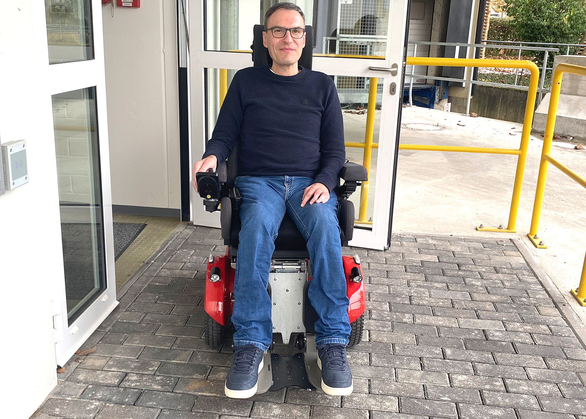 Schäfffers in einem E-Rollstuhl vor der Eingangstür
