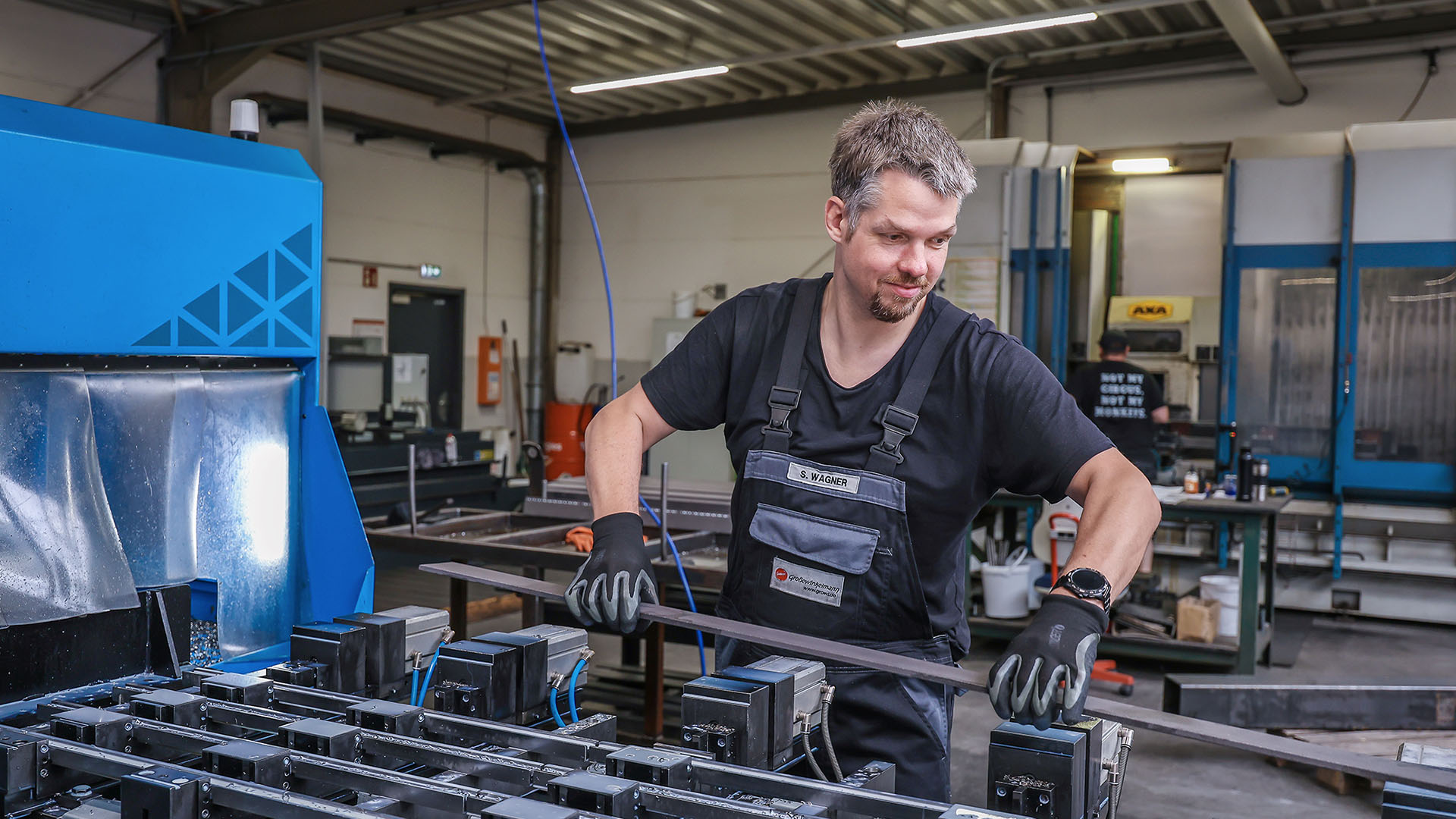 Stefan Wagner steht an einer großen Industrie-Maschine in einer Werkshalle.