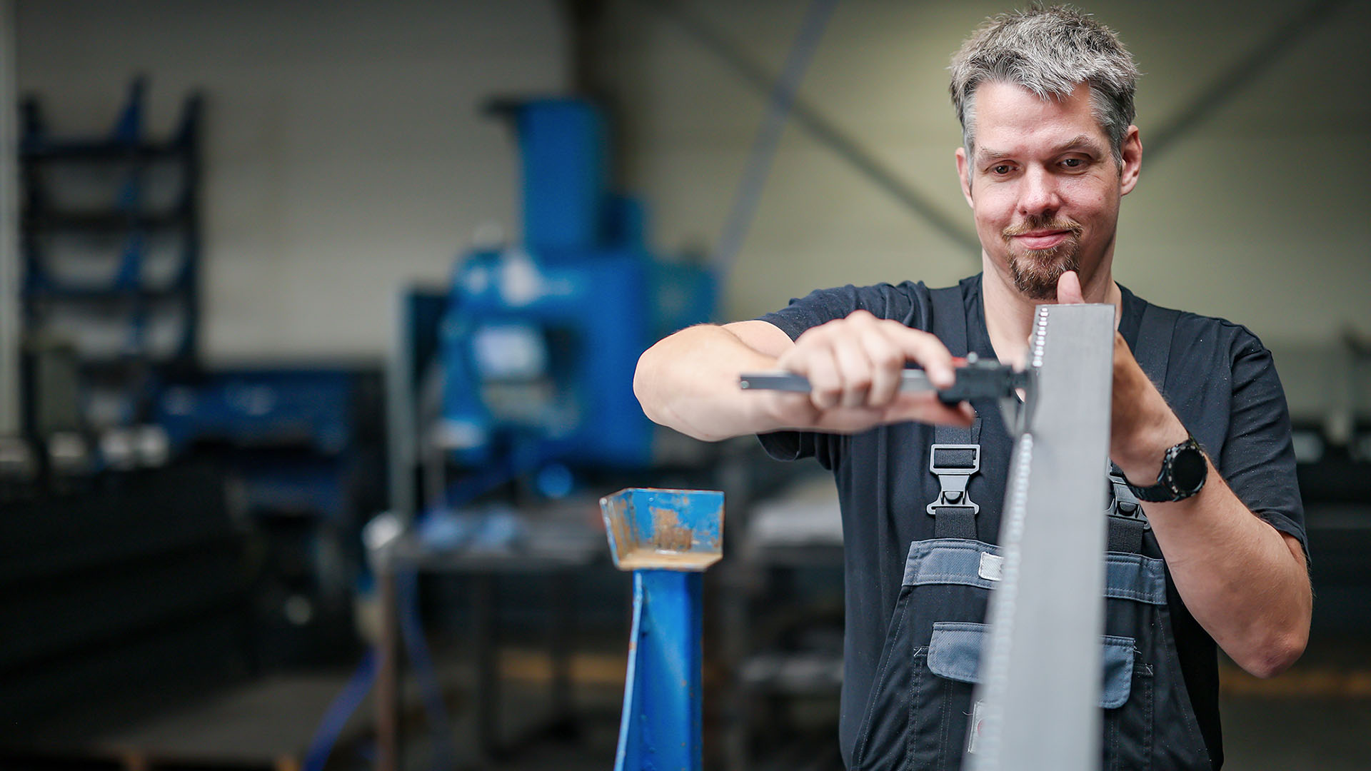 Wagner hält eine Metallleiste in der Hand und überprüft diese.
