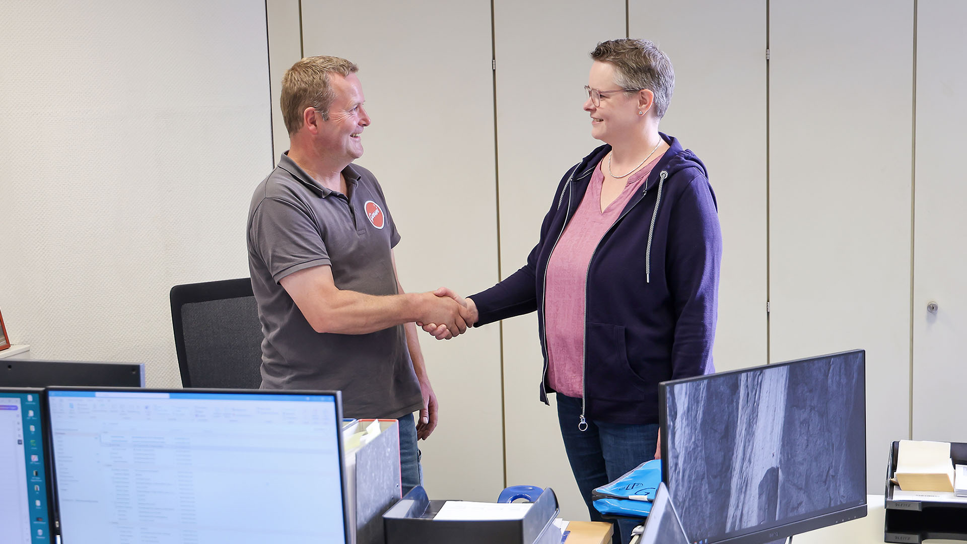 Karin Kirchner und Matthias Vogelsang begrüßen sich im Büro.