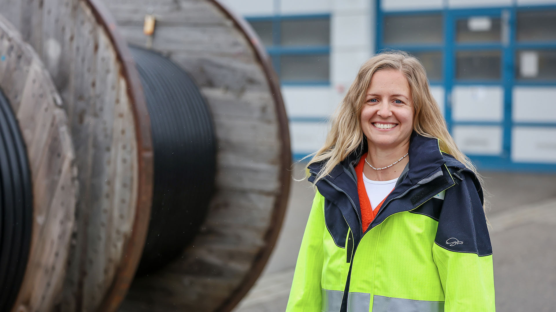 Eva Hagenbucher steht neben einer riesigen Kabeltrommel, die größer ist als sie selbst.