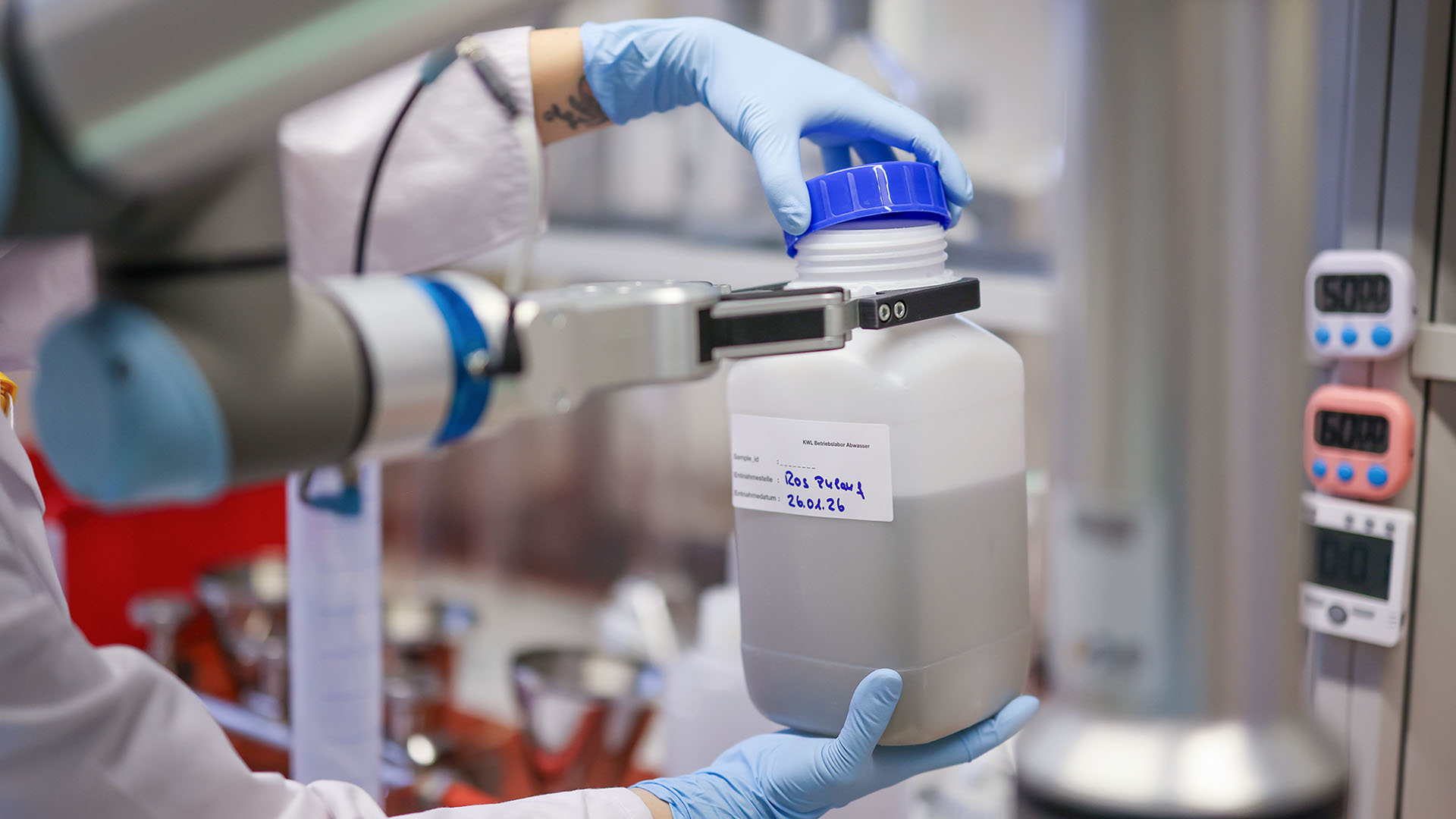 Ein 1-Liter-Container mit Proben wird in den Cobot eingespannt. 