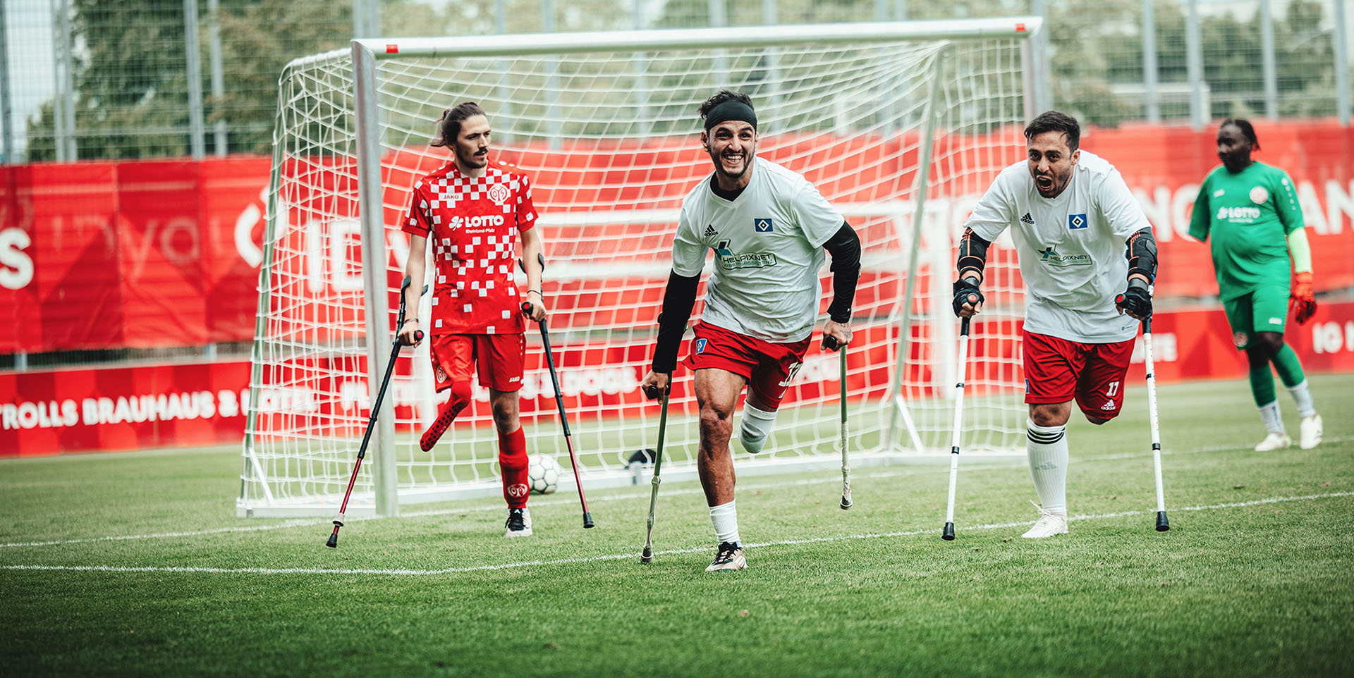 Mehrere Fußballspieler mit einem amputierten Bein laufen auf Krücken über den Fußballplatz.