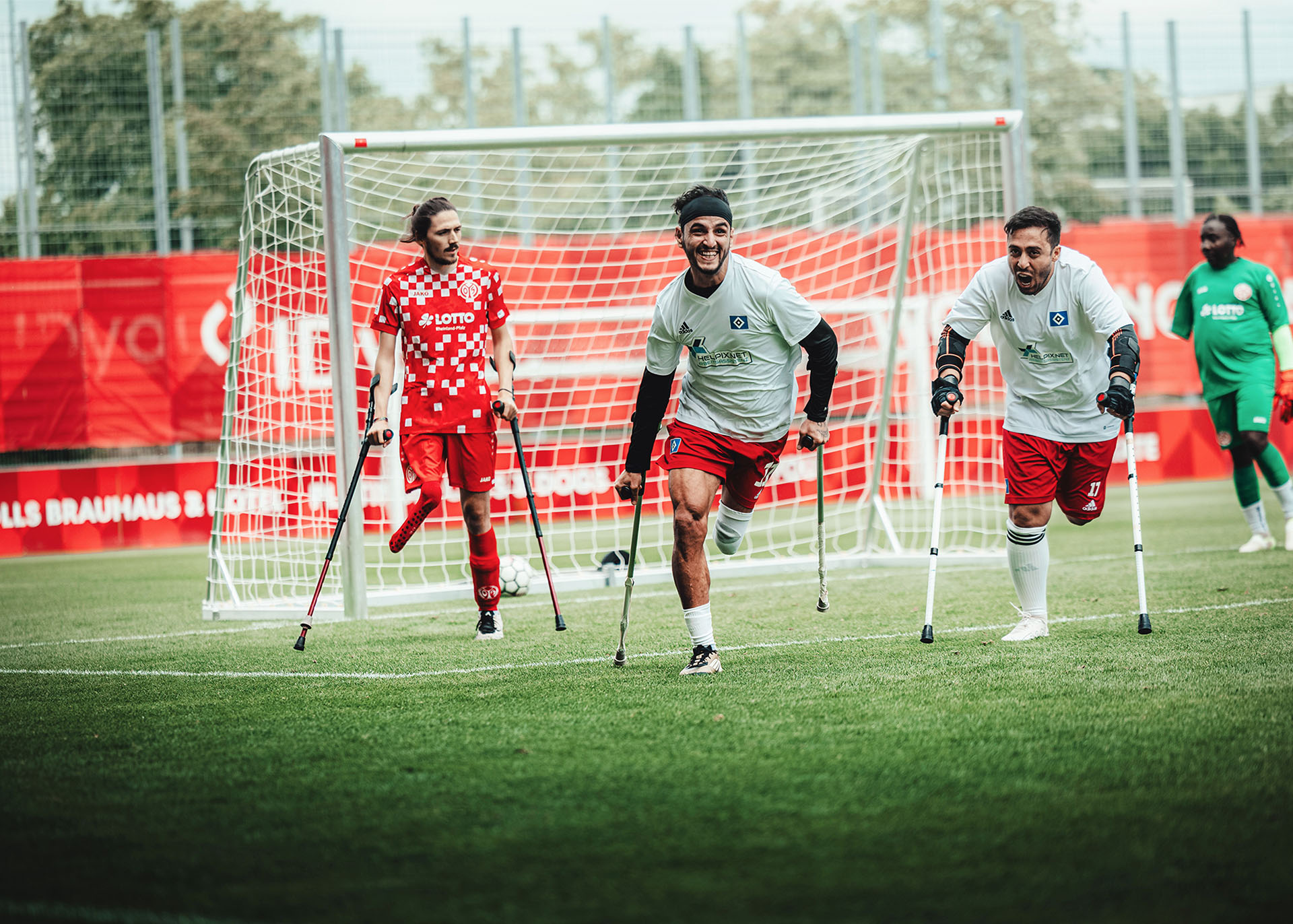 Mehrere Fußballspieler mit einem amputierten Bein laufen auf Krücken über den Fußballplatz.