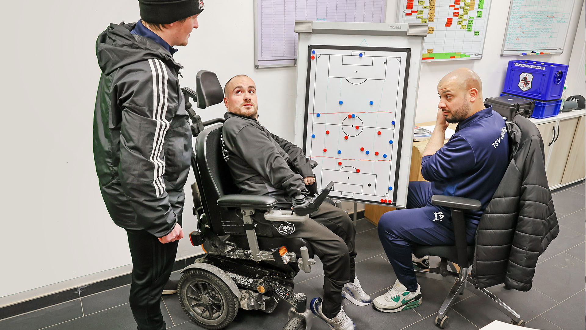Im Trainerteam werden Spielzüge gemeinsam besprochen, drei Personen vor einem Flipchart mit Spielzügen