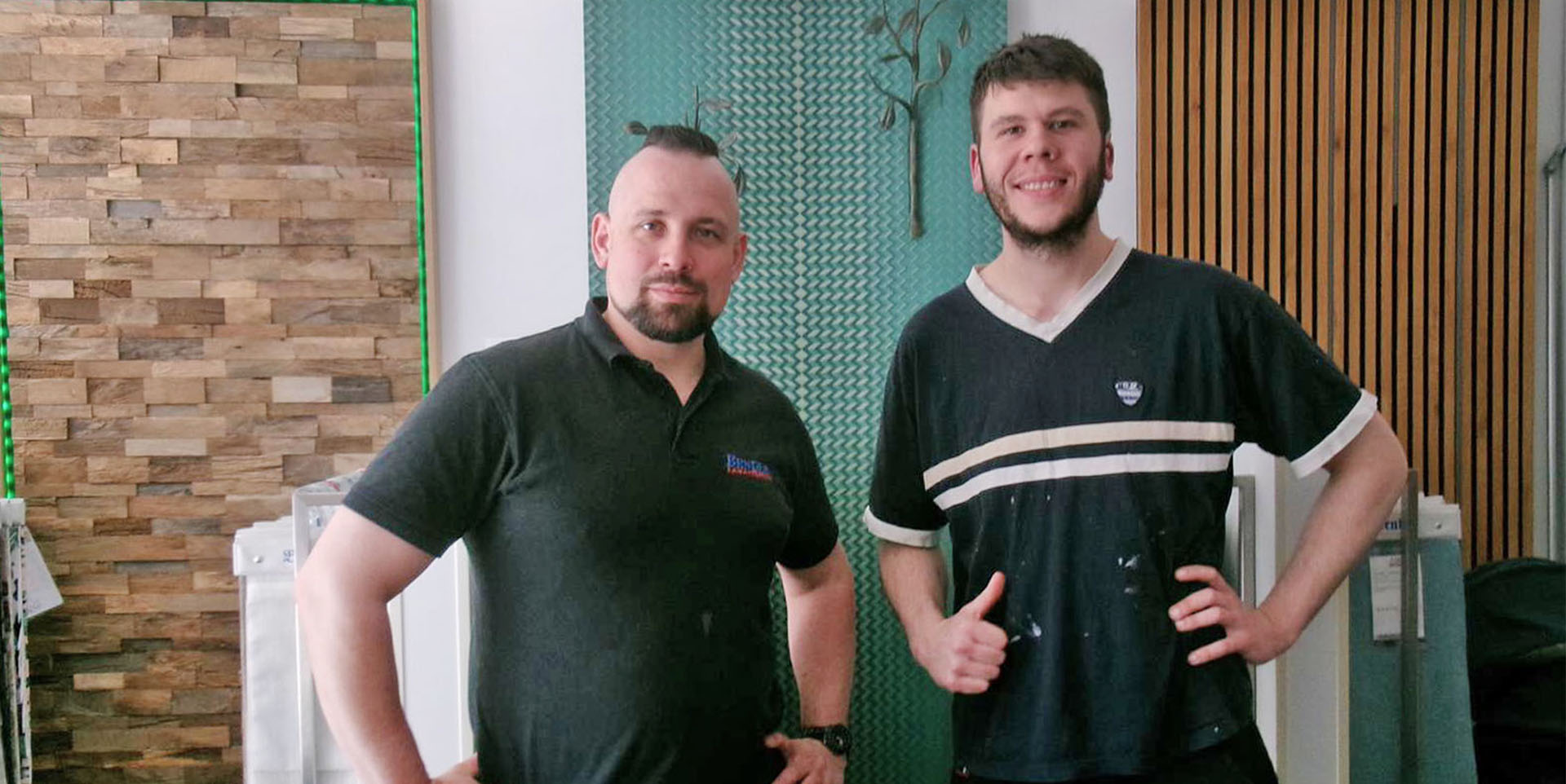 Christian Bender und Jean-Michel Hess stehen zusammen vor verschiedenen Musterwänden im Raumausstatterbetrieb.