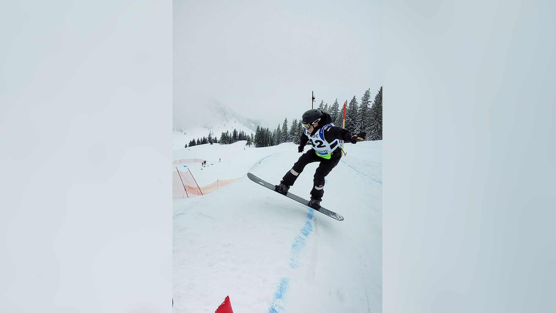 Ein Snowboardfahrer fährt über eine Cross-Strecke. 