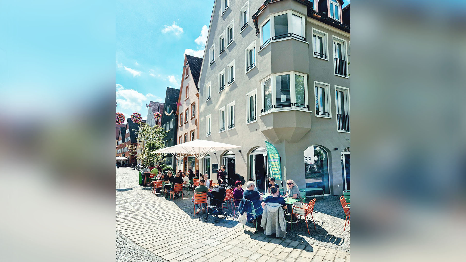Das Foto zeigt eine Außengastro in einer ruhigen, geplasterten Gasse mit gepflegten alten Häusern. 